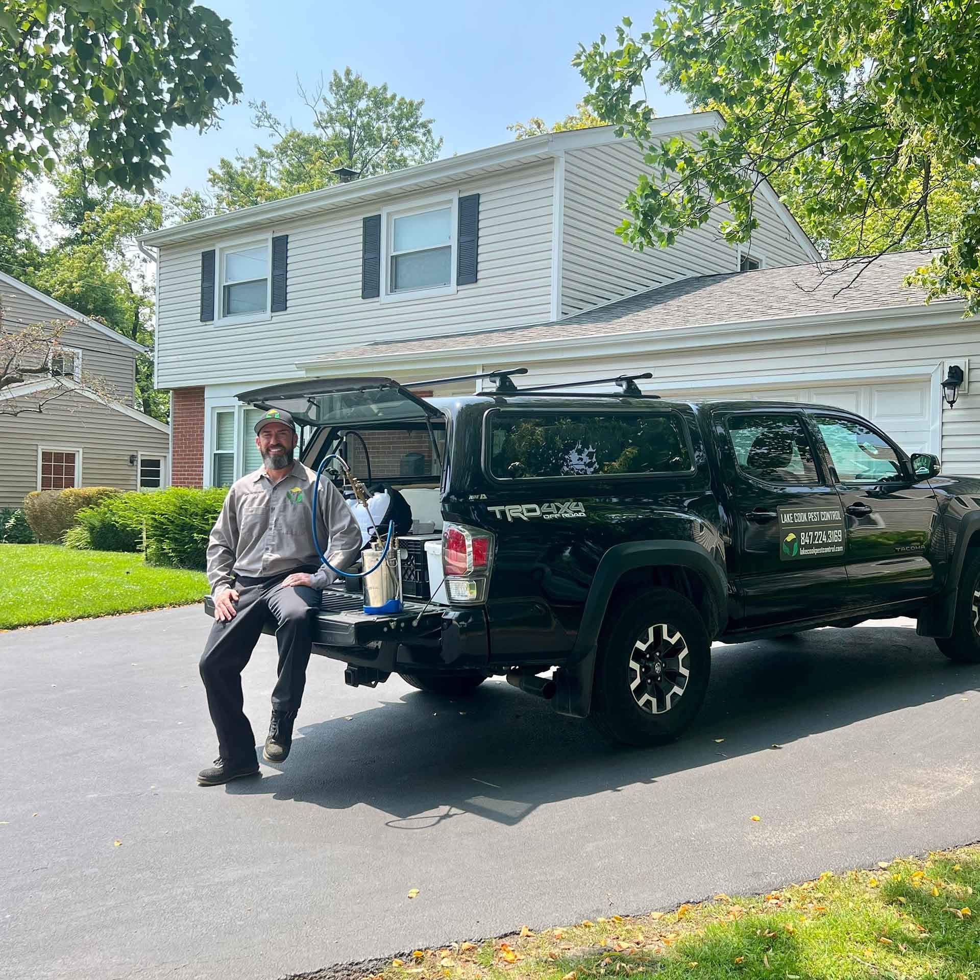 Lake Cook Pest Control technician beside the company truck in a residential driveway